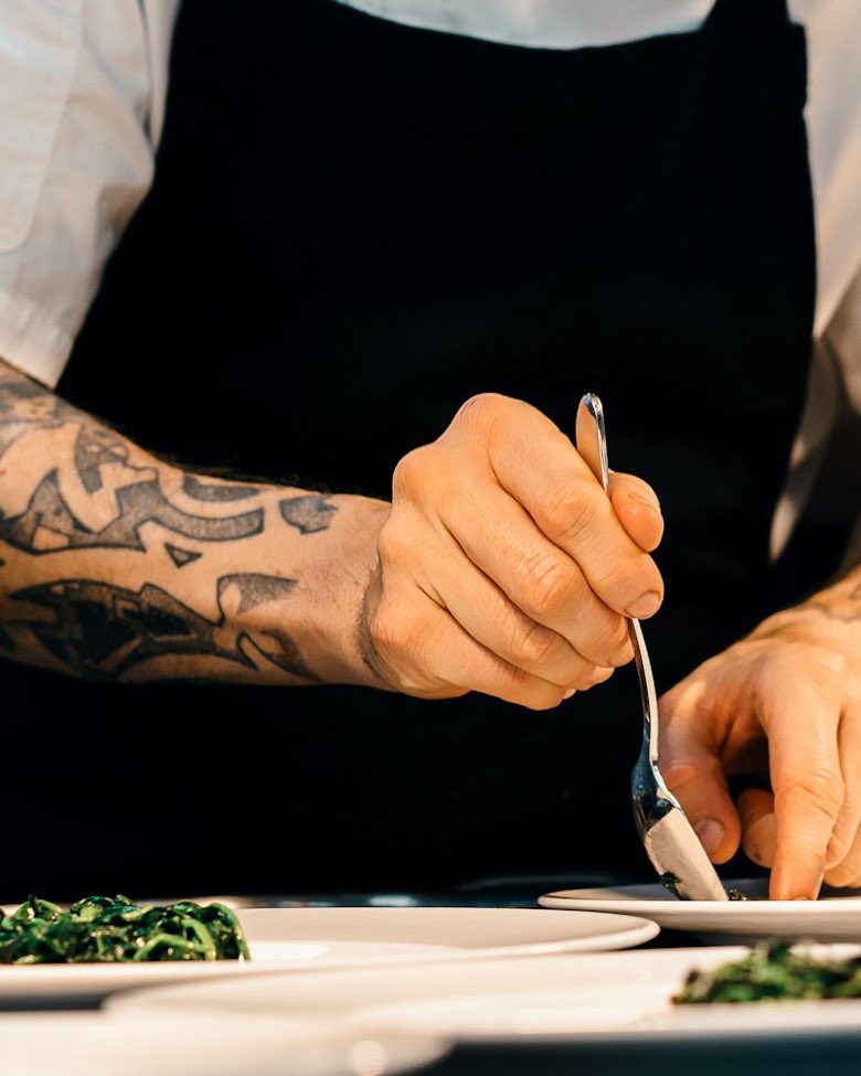 Cocinero emplatando sobre una mesada de acero