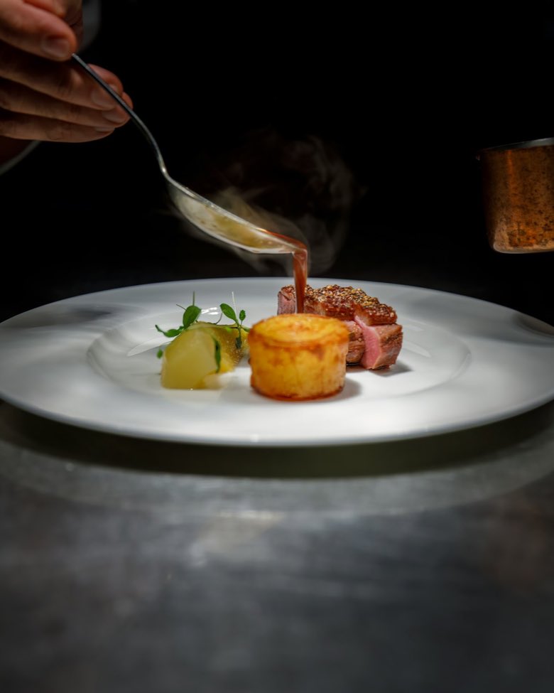 Cocinero terminando un plato con una salsa