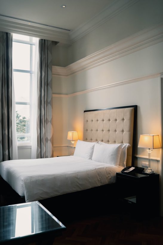 Dormitorio con ropa de cama blanca y mesa de luz de madera