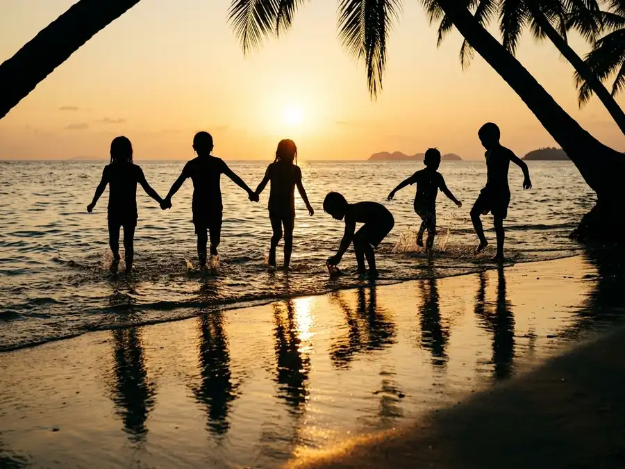 Siluetas de chicos jugando en el agua de la orilla contra el sol del atardecer